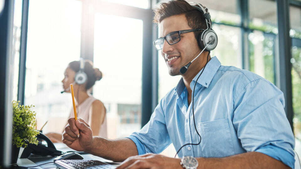 A man in a headset is working on a computer.