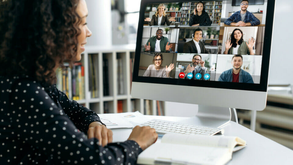 A woman sitting in front of a computer with several people on a video conference.